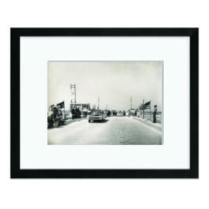 Black-and-white photo of people gathered on a boardwalk, framed with a wide white mat and black frame.